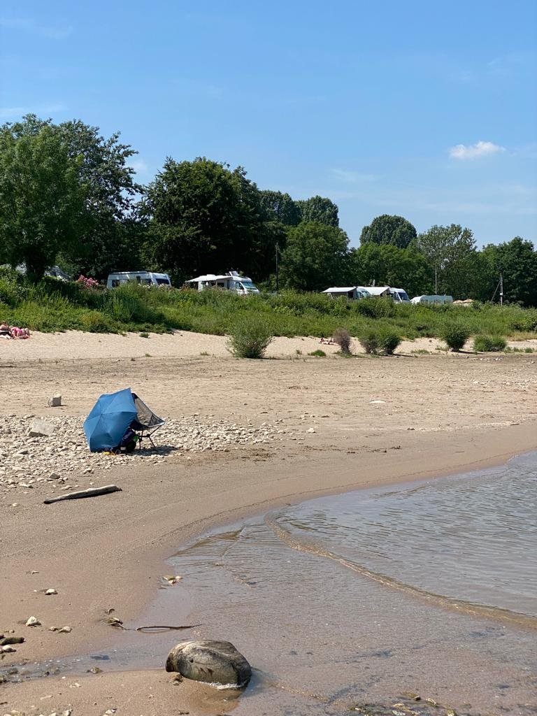 Beautiful beach with a small size umbrella and a foldable chair to use as a solution for people living with MS that want to enjoy their life